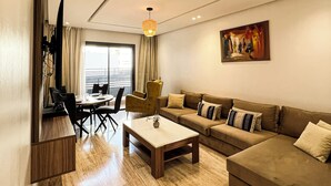 Ein modernes Wohnzimmer mit einer Sofagarnitur, einem Essbereich und einem an der Wand befestigten Fernseher.