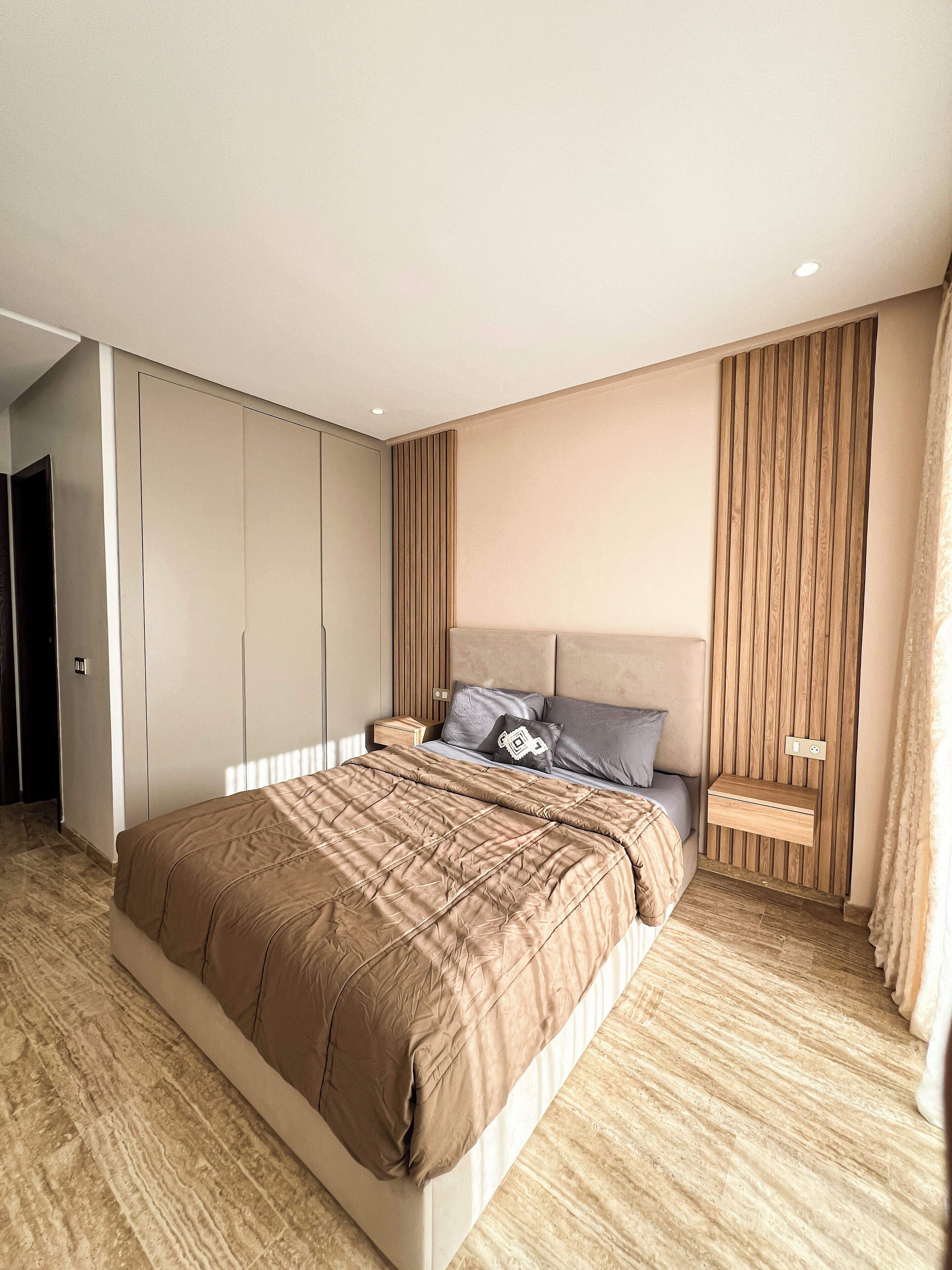 Un dormitorio moderno con una cama grande, armario empotrado y una mesita de noche con lámpara.