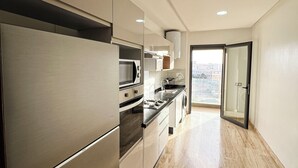 Eine moderne Küche mit Edelstahlgeräten, einer Holzausziehtafel und Blick auf die Stadt durch eine Glastür.