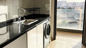 Eine moderne Küche mit eingebauter Waschmaschine, einem großen Fenster und Blick auf die Stadt.