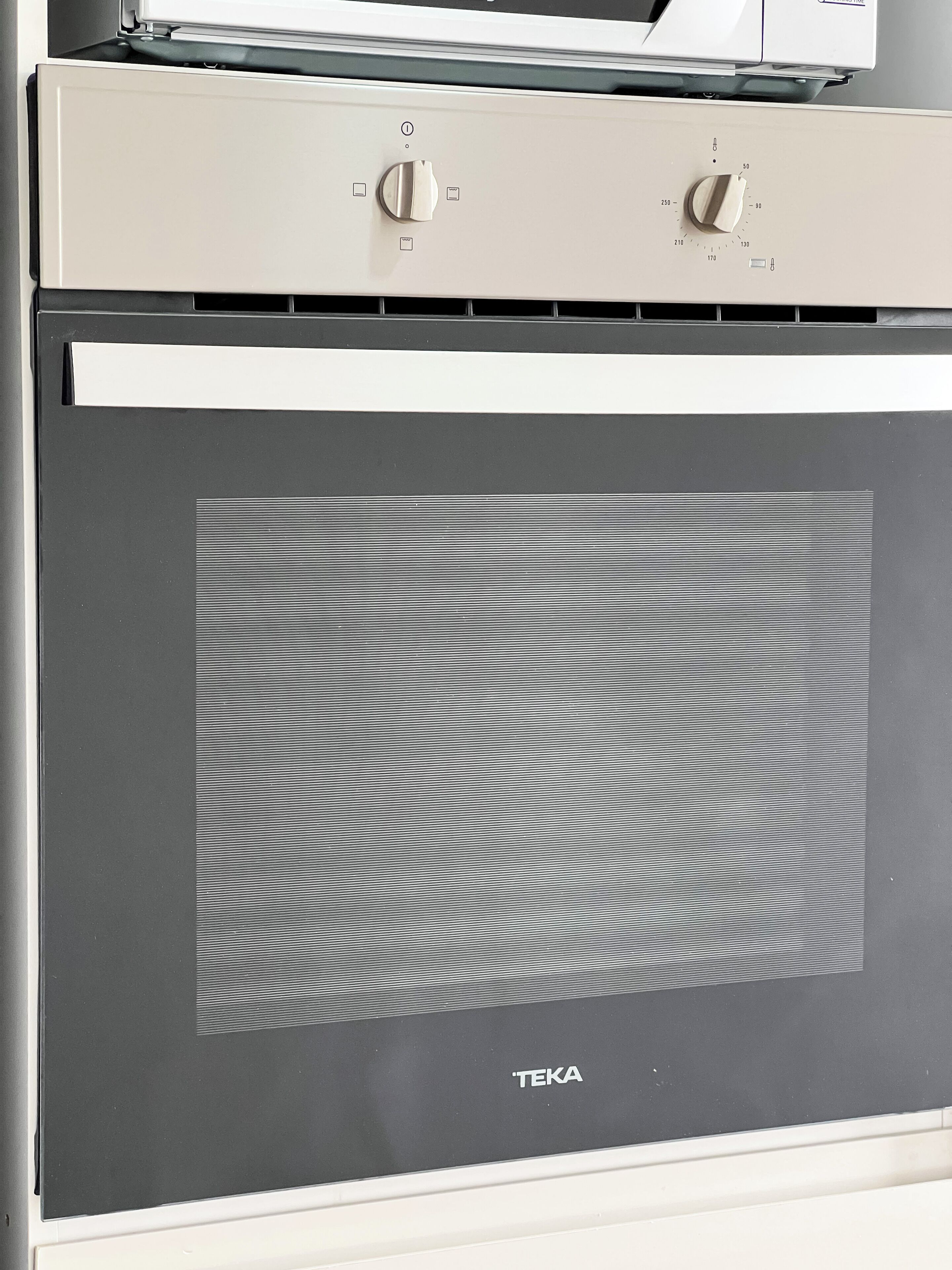 Una cocina con horno empotrado y microondas encima.