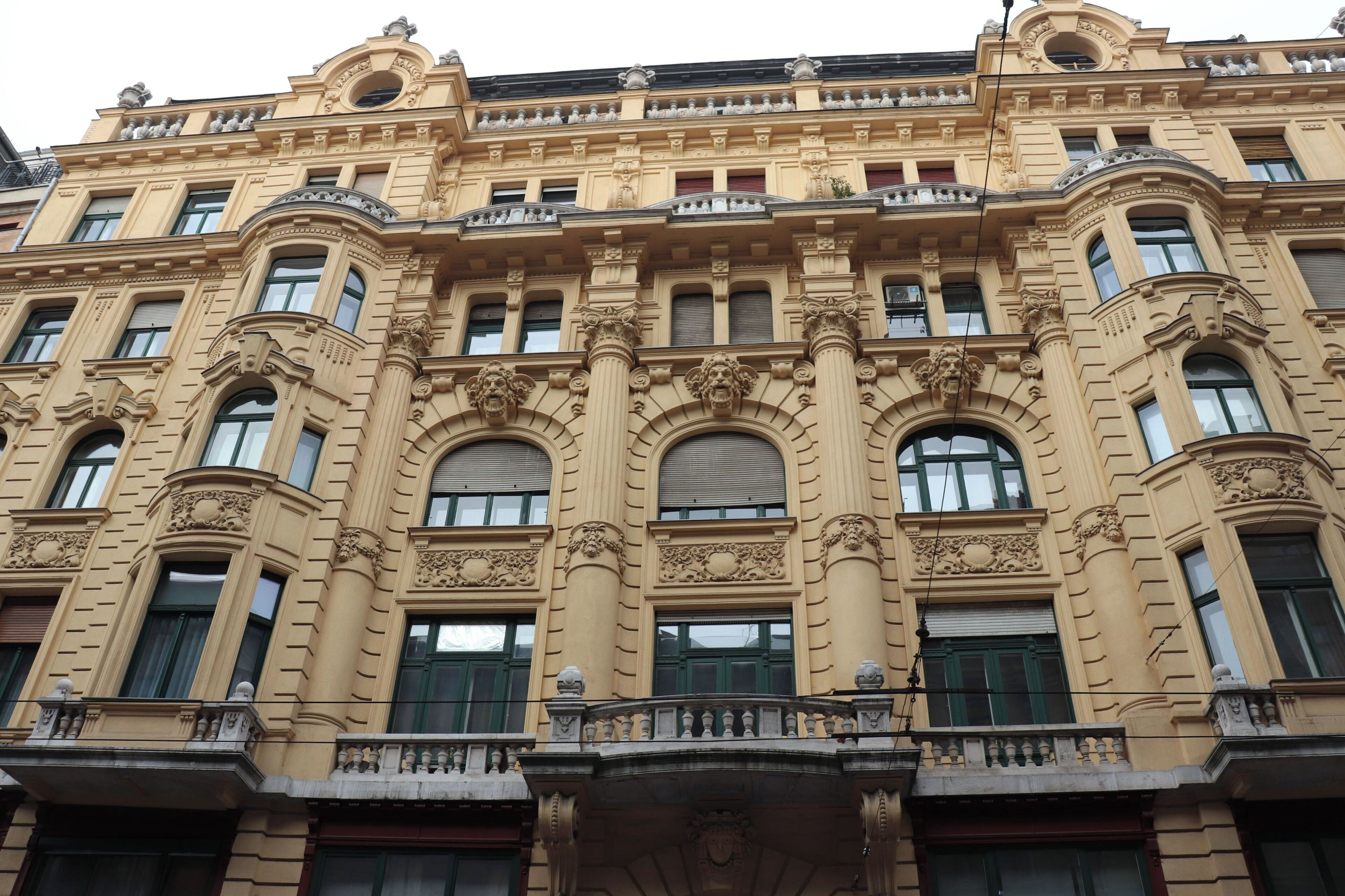Ein historisches Gebäude mit aufwendigen architektonischen Details, zahlreichen Fenstern und einem Balkon.