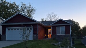Ein zweistöckiges Haus mit Garage, Veranda und kleinem Vorgarten.