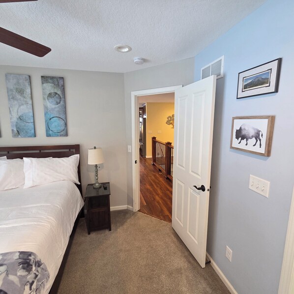 A bedroom with a bed, nightstand, lamp, and artwork on the wall. - CherryWood Home-2 miles from Downtown & Mayo Clinic (Rochester)
