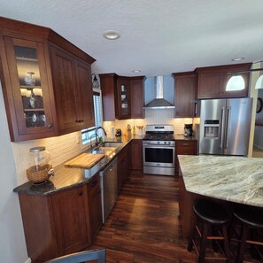 A kitchen with wooden cabinets, a stainless steel stove, and a refrigerator. - CherryWood Home-2 miles from Downtown & Mayo Clinic (Rochester)