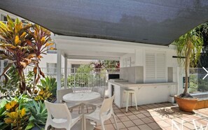 An outdoor patio area with a round table and chairs, a small bar area, and various potted plants. - Immaculate Fully Self Contained Apartment in Central Surfers Paradise (Surfers Paradise)