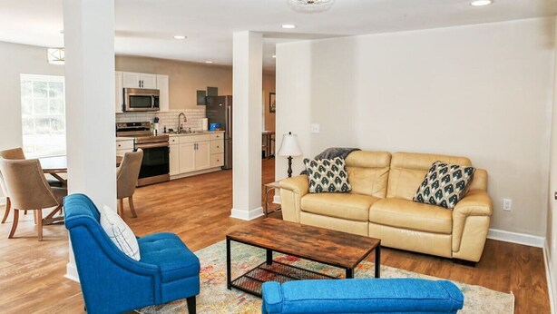 Una sala de estar con un sofá color crema, sillones azules y una mesa de centro.
