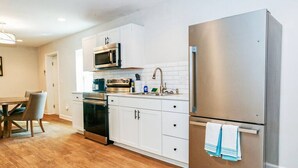 Una cocina moderna con armarios blancos, electrodomésticos de acero inoxidable y una mesa de comedor de madera.