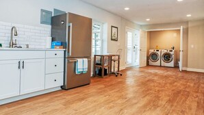 Una cocina moderna con armarios blancos, un refrigerador de acero inoxidable y una mesa de comedor de madera.