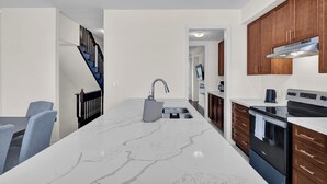 A modern kitchen with a marble countertop, a built-in oven, and wooden cabinets. - Embers Nest - 5 beds, 4 baths, 2 park, Backyard, Thermea Spa (Whitby)