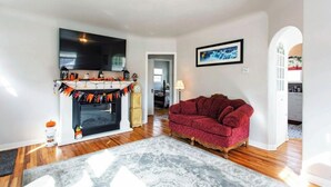 A living room with a fireplace, a red sofa, and a flat-screen TV mounted on the wall.
