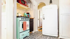 A kitchen with a vintage stove, a microwave, and a refrigerator.