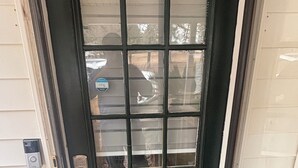 A black door with a glass panel, a keypad lock, and a doormat with paw prints.