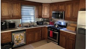 A kitchen with wooden cabinets, a stove, a microwave, and a refrigerator.