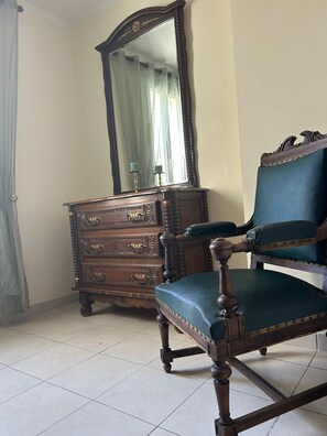 Une pièce comprenant une commode en bois, une chaise, un miroir et un rideau.