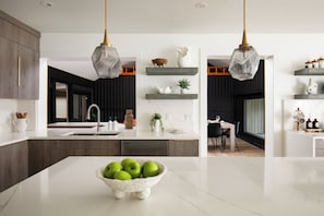 Een moderne keuken met een centraal eiland, hanglampen en inbouwplanken.