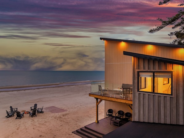 Een strandhut met een terras, zitplaatsen buiten en een vuurkuil.
