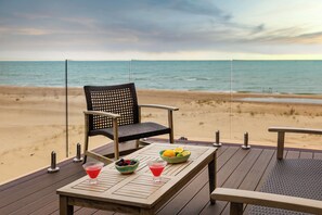 Een houten terras met een tafel, stoelen en uitzicht op het strand en de oceaan.