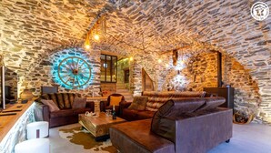 Ein rustikales Stein-Interieur mit einem großen Holzwagenrad, Ledersofas und einem Holztisch.