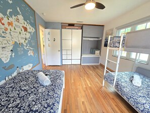 Habitación pequeña con dos literas, un armario, una puerta y un mapa en la pared.