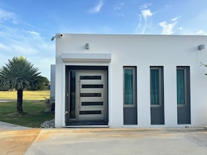 Ein modernes Gebäude mit weißer Fassade, einer großen Glastür und drei vertikalen Fenstern.