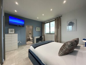 Ein Schlafzimmer mit Bett, Schreibtisch, Kleiderschrank, Fernseher und einem Fenster mit Vorhängen.