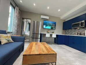 Eine moderne Küche mit blauen Schränken, einem Edelstahlkühlschrank, einer Mikrowelle und einem Fernseher an der Wand.