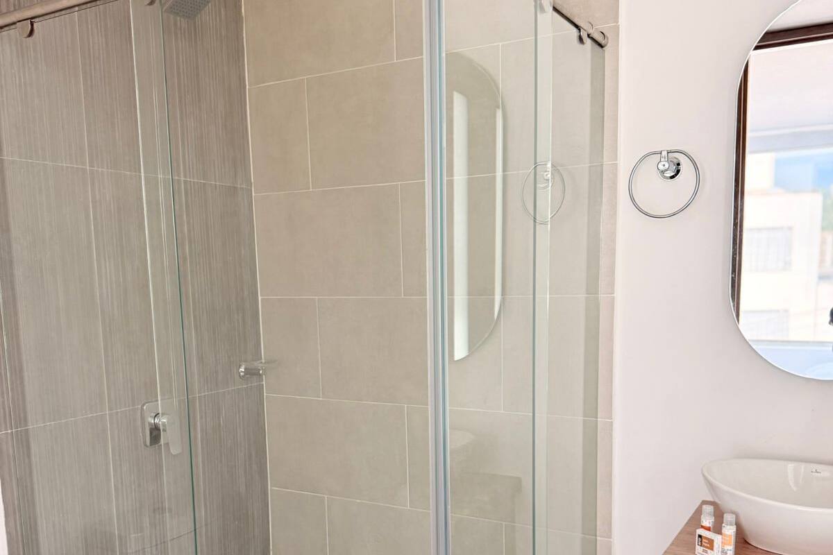 Une salle de bain moderne avec une douche à parois de verre, un lavabo blanc et un meuble-lavabo en bois.