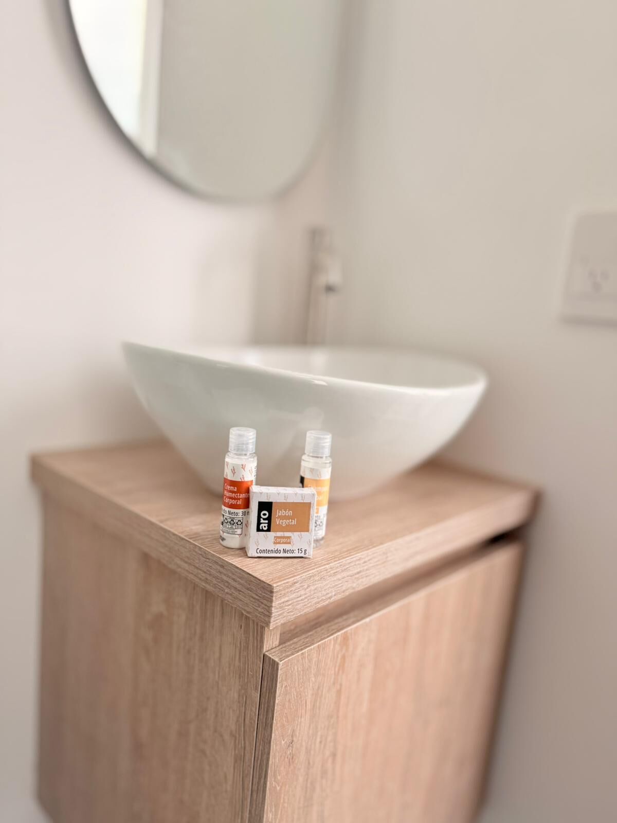 A bathroom with a wooden vanity, a white sink, and two bottles of soap on the countertop.