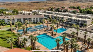 Un resort con varias edificaciones, una piscina central y palmeras circundantes.