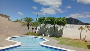 Una piscina con diseño geométrico, rodeada por un muro de hormigón y pequeños árboles.