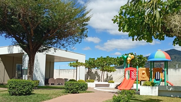Un parque infantil con toboganes y estructuras para escalar, rodeado de césped cuidado y árboles.