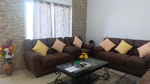 Un salón con dos sofás marrones, una mesa de centro de cristal y una pared de acento de piedra.