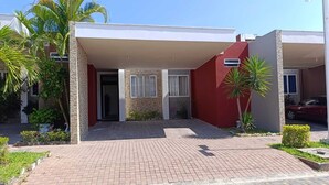 Una casa moderna de dos pisos con un porche cubierto, un camino de entrada pavimentado y una pared exterior roja.