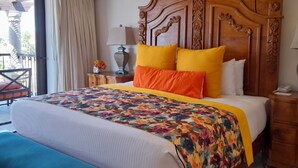 Ein Hotelzimmer mit einem großen Bett, einem Holzkopfende, einer Bank, einem Nachttisch und einer Lampe.