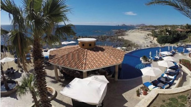 Ein Resort mit Poolbereich, Liegestühlen und Blick auf den Strand.