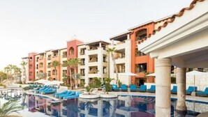 Ein Hotelpoolbereich mit mehreren Balkonebenen, Liegestühlen und einem klaren Pool.