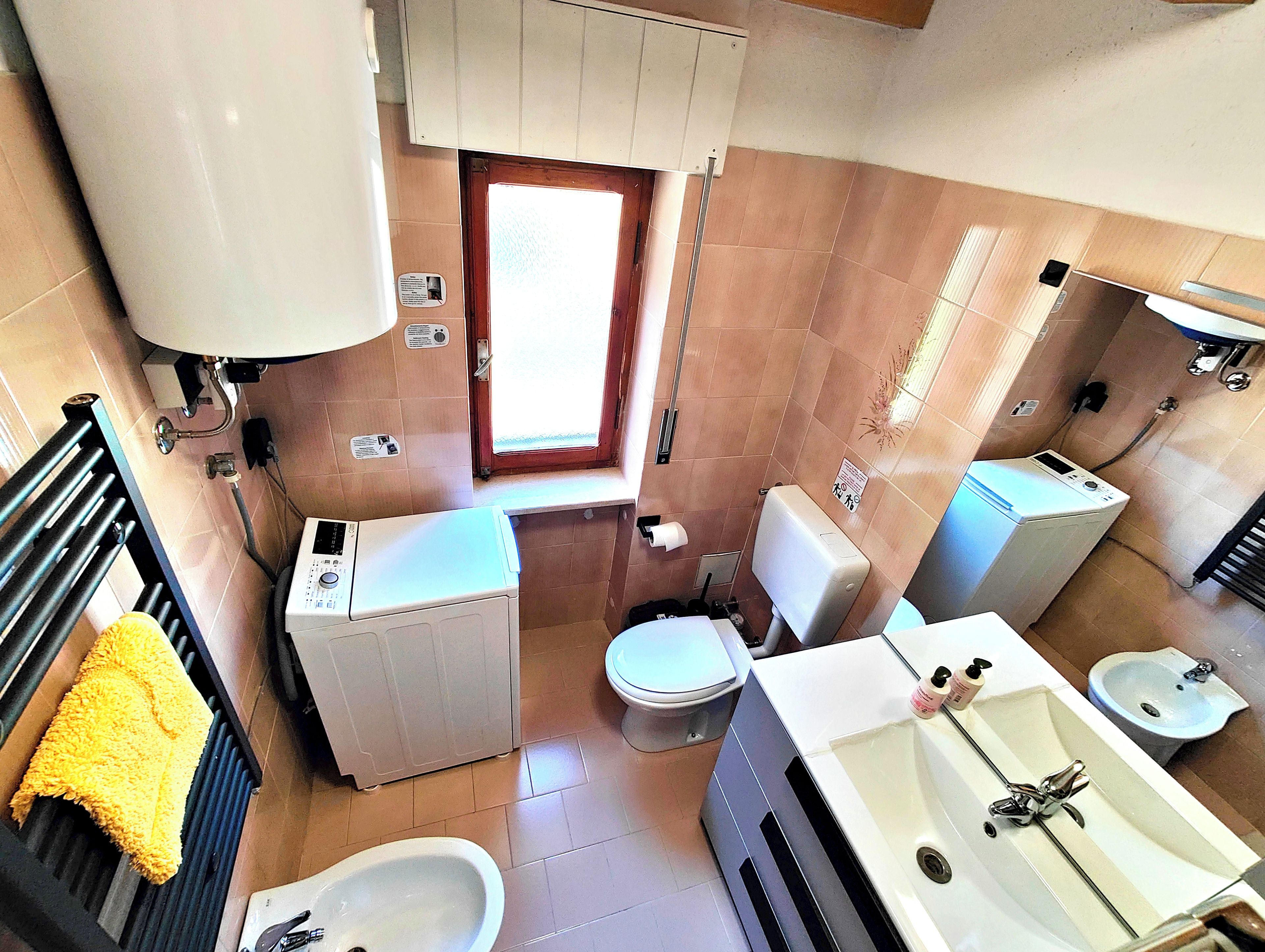Ein kleines Badezimmer mit Toilette, Bidet, Waschmaschine und Waschbecken.