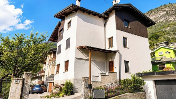 A two-story building with a balcony, a satellite dish, and a visible number '92' on the wall.