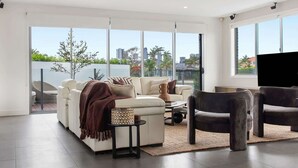 Ein modernes Wohnzimmer mit einer Couch, Sesseln und einem Fernseher.