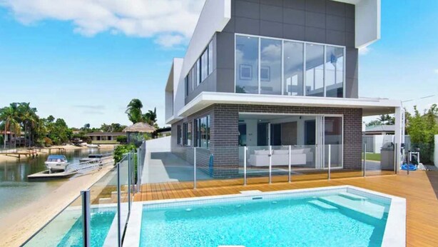 Ein modernes, zweistöckiges Gebäude mit Pool, Bootsanleger und Blick auf das Wasser.