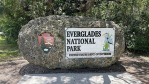 Ein großer Felsen mit Schildern für den Everglades Nationalpark und den Nationalparkdienst.