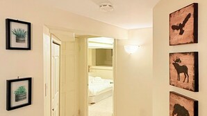 A hallway with a carpeted floor, a door leading to a bedroom, and framed artwork on the walls. - Cozy 3 bedroom suite in heart Kitsilano, close to kits beach & downtown (Vancouver)