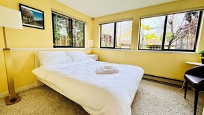 A hotel room with a large bed, two windows, a bedside table, and a chair. - Cozy 3 bedroom suite in heart Kitsilano, close to kits beach & downtown (Vancouver)