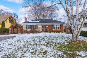 A single-story house with a brick facade, a front porch, and a snow-covered lawn.