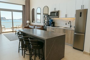 Una cocina moderna con una isla de granito, electrodomésticos de acero inoxidable y vistas al mar.