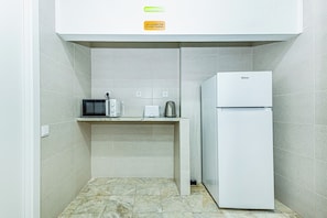A compact kitchenette with a microwave, toaster, and a white refrigerator. - Arbutus Bed & Bar (Portimão)