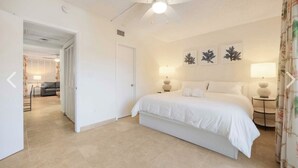 Une chambre à coucher comprenant un lit, deux tables de chevet, un ventilateur de plafond et des lampes fixées au mur.