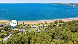 An aerial view of a coastal residential area with houses, a beach, and a large body of water.