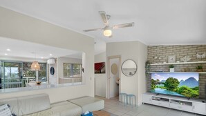A modern living room with a sofa, coffee table, TV, and a ceiling fan.